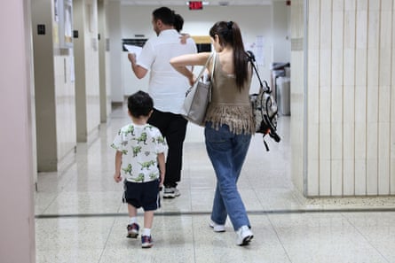 A man, a woman and a small child walk down a tiled corridor.