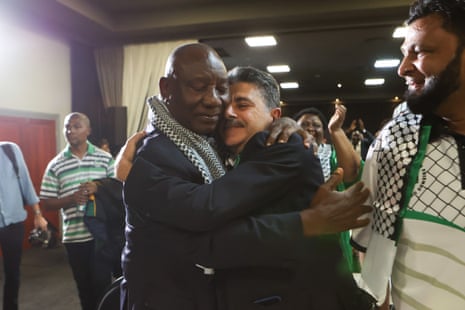 South African president Cyril Ramaphosa and the deputy ambassador of Palestine, Bassam Elhussiny hug as they watch the ICJ ruling on the emergency measures requested by South Africa against Israel over its war on the Gaza Strip, in Johannesburg.