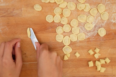Pushing a butter knife into a piece of pasta dough to form orecchiette.