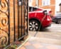 A charge gully with a car on charge in the street with a metal gate open against a brick wall in the foreground