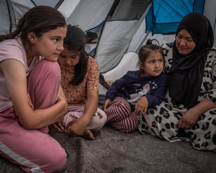 A woman and child sit inside a tent