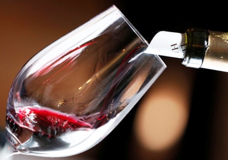 Red wine is poured into a wine glass.