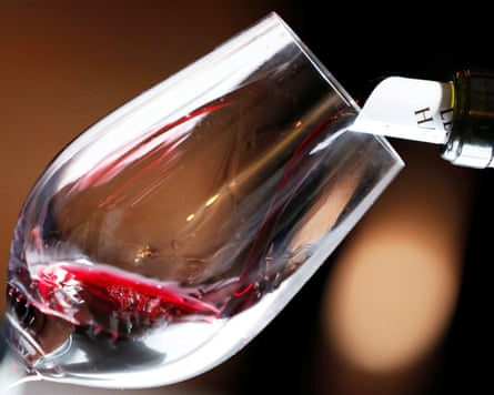 Red wine is poured into a wine glass.