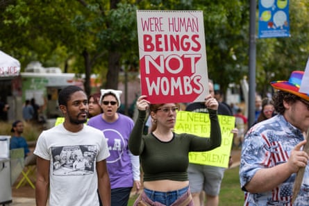 Woman holds sign that says We’re Human Beings, Not Wombs.