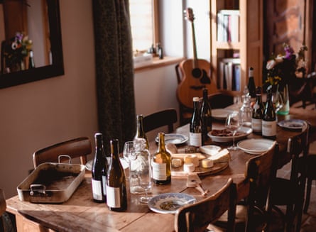 A table in a lodge with wine and cheese on it and a guitar in the background