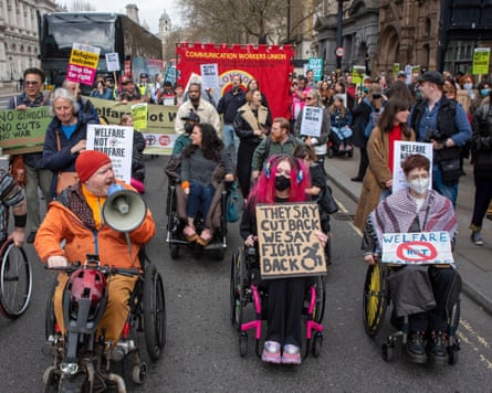 A protest led by several people with disabilities in wheelchairs and scooters holding signs