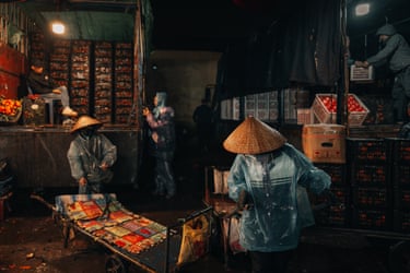 night workers in bamboo hats and waterproof clothing unpack preparing produce for the night market