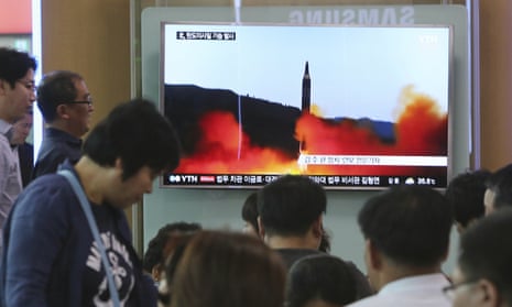 People watch a TV news program showing a file image of a missile launch by North Korea