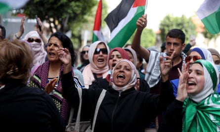 Women in a crowd shouting and waving flags.
