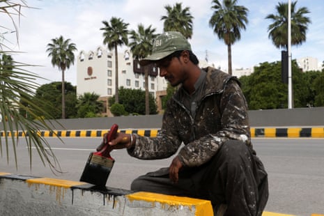 A worker paints the sidewalks ahead of the visit of US and Iranian delegations to Islamabad.