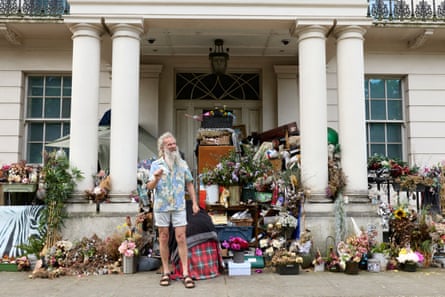 He stands smiling in front of his belongings, which are strewn across the porch of the home