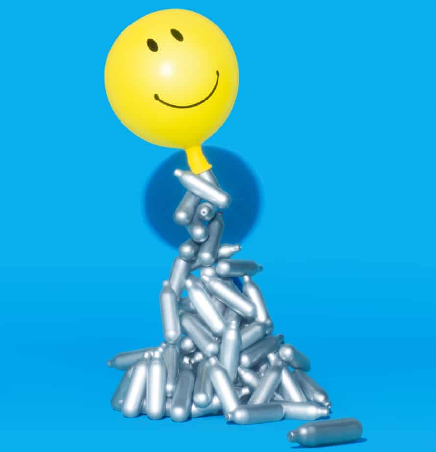 Composite of balloon with a smily face carrying laughing gas canisters against a blue background
