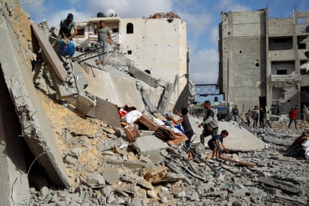 People carry items over a destroyed building