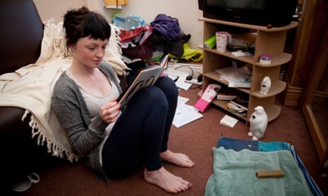 A young woman UK university student reading a book in the living room of her house flat bedsitC2M2G1 A young woman UK university student reading a book in the living room of her house flat bedsit