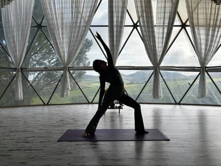 Woman in an upright yoga pose, silhouetted against the triangular windows of a geodesic dome
