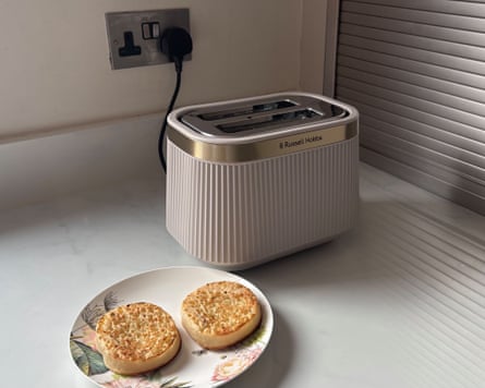 A beige Russell Hobbs Brontë 2S Toaster on a worktop next to a plate with two toasted crumpets