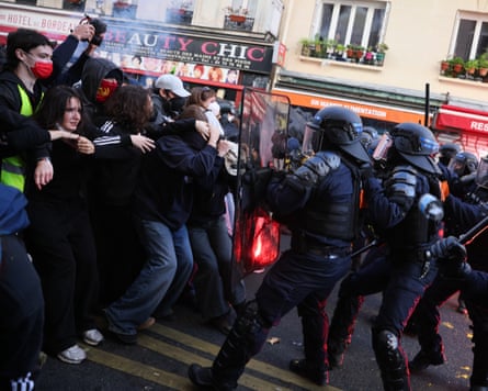 Riot police with shields and batons push against protesters during a Paris demonstration
