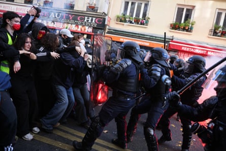 Riot police with shields and batons push against protesters during a Paris demonstration