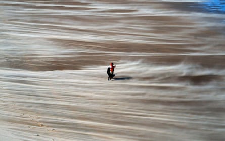 People walk along Tynemouth beach in the north-east during strong winds.
