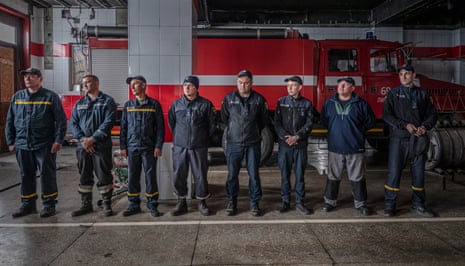 A group of firefighters lined up in front of a fire engine