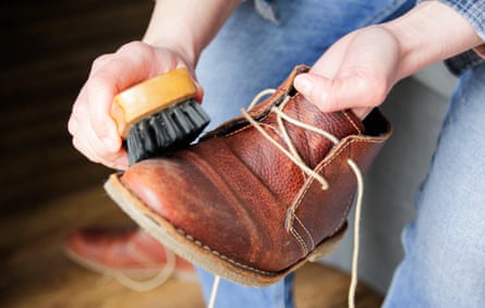 A person brushing a leather boot