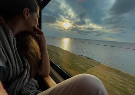 Woman looking out of a train window at the sea and a causeway