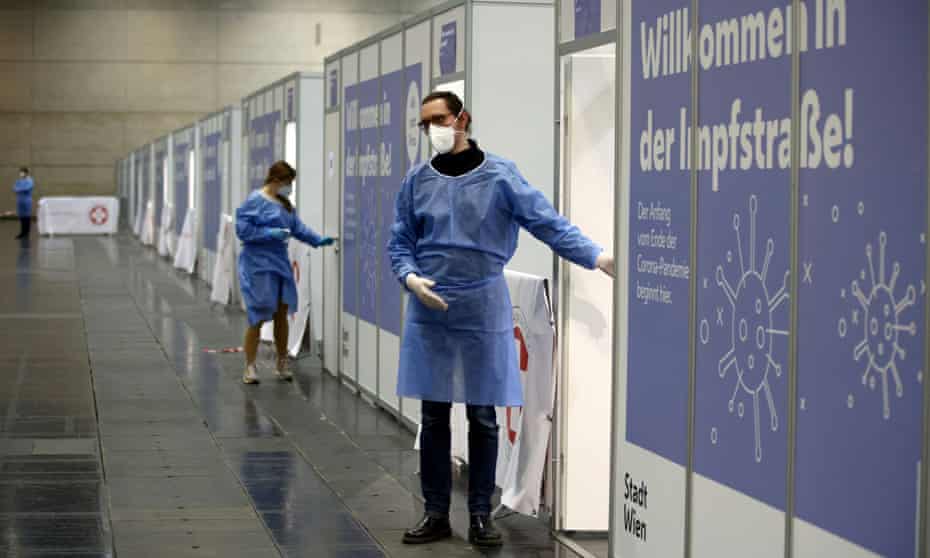 People wait for vaccinations in Vienna, Austria, in front of signs reading ‘Welcome to vaccination street’.