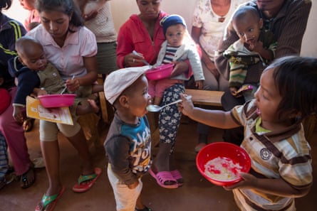 Mothers (and a father) and their malnourished children eat a meal of rice, marrow, dried shrimp, carrots, oil and iodised salt during a nutrition class in Antsirabe