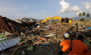 A rescue team uses an excavator to search for bodies under the ruins of the house at Petobo village
