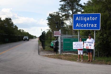 Protesters Leo and Catherine Gentile held signs near the entrance to the Florida Everglades immigration detention center state officials call Alligator Alcatraz, in Ochopee, Florida last August.