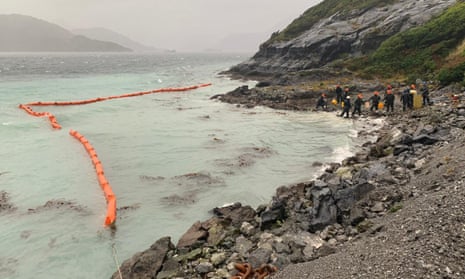 Sailors work to contain damage from an oil spill, on Guarello Island in Patagonia, Chile