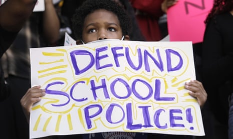 A child holding up a poster reading 'Defund School Police!'