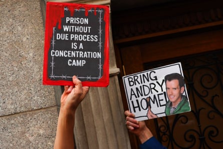 Hands hold signs that read ‘prison without due process is a concentration camp’ and ‘bring Andry home’ with a picture of the makeup artist.