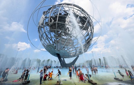 People enjoy refreshing water of a fountain in the Unisphere fountain at Flushing Meadow Corona Park in the borough of Queens on 21 July 2019 in New York City.