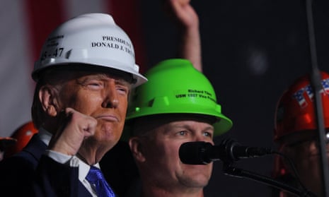 Donald Trump in a hard hat reading 'President Donald J Trump' pumping his fist on stage next to a steelworker