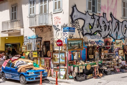 A vintage items shop in Athens with graffiti on the wall and a car.