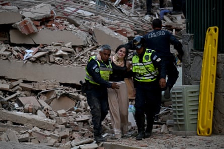 Municipal police officers evacuate an injured person from a collapsed building