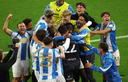 Huddersfield’s Lee Nicholls is mobbed by his teammates.