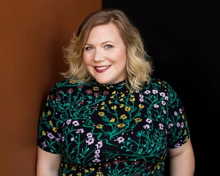 Lindy West pictured from the waist up, wearing a floral dress and smiling at the camera