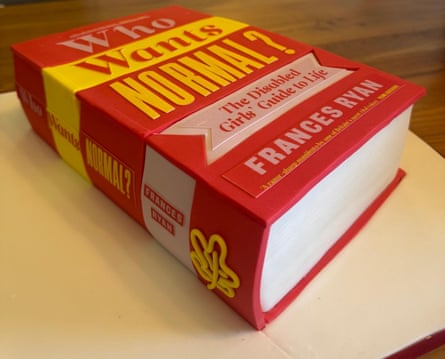 A big red book with yellow and white details and white pages – in cake form – on a table.