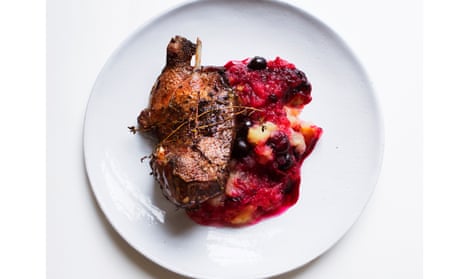Roast duck with apple and blueberry sauce on a round white plate