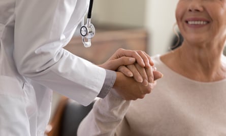 Young female physician leaning forward to smiling elderly lady.