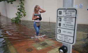 A woman walks through a flooded street that was caused by the combination of the lunar orbit which caused seasonal high tides and what many believe is the rising sea levels due to climate change, in September in Miami Beach, Florida. 