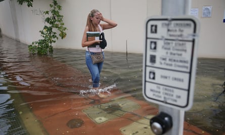 A woman walks through a flooded street in Miami Beach. The flood was caused by the combination of the lunar orbit, which generated seasonal high tides, and what many believe is the rising sea levels due to climate change.