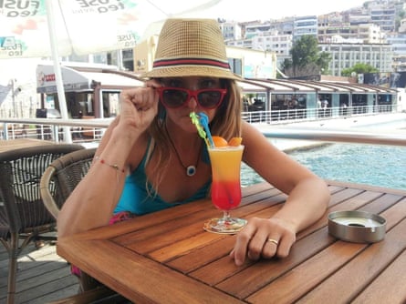 Lisa Bench sips a colourful drink while wearing a hat and sunglasses
