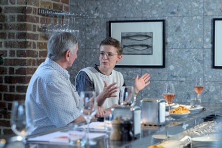 A man and woman facing each other, side by side at a restaurant table