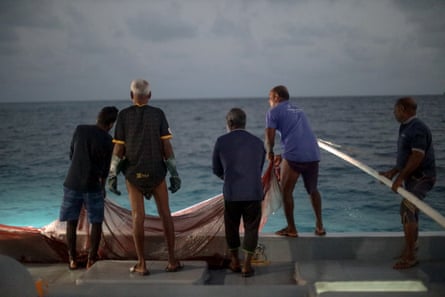 Five men haul in a net in the dawn light