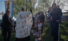 Priest performing blessing; religious banner; people in front of him, some crossing themselves and one with crutch