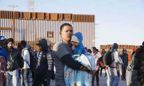 A man holds a baby, in a large crowd, as migrants face long wait times for border patrol officers at the USA border with Mexico, on the last day of Title 42, in Yuma, Arizona, on May 11, 2023.