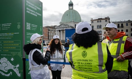 Municipal workers of Venice stand next to an information totem for entering the city, in front of the Santa Lucia railway station in Venice.